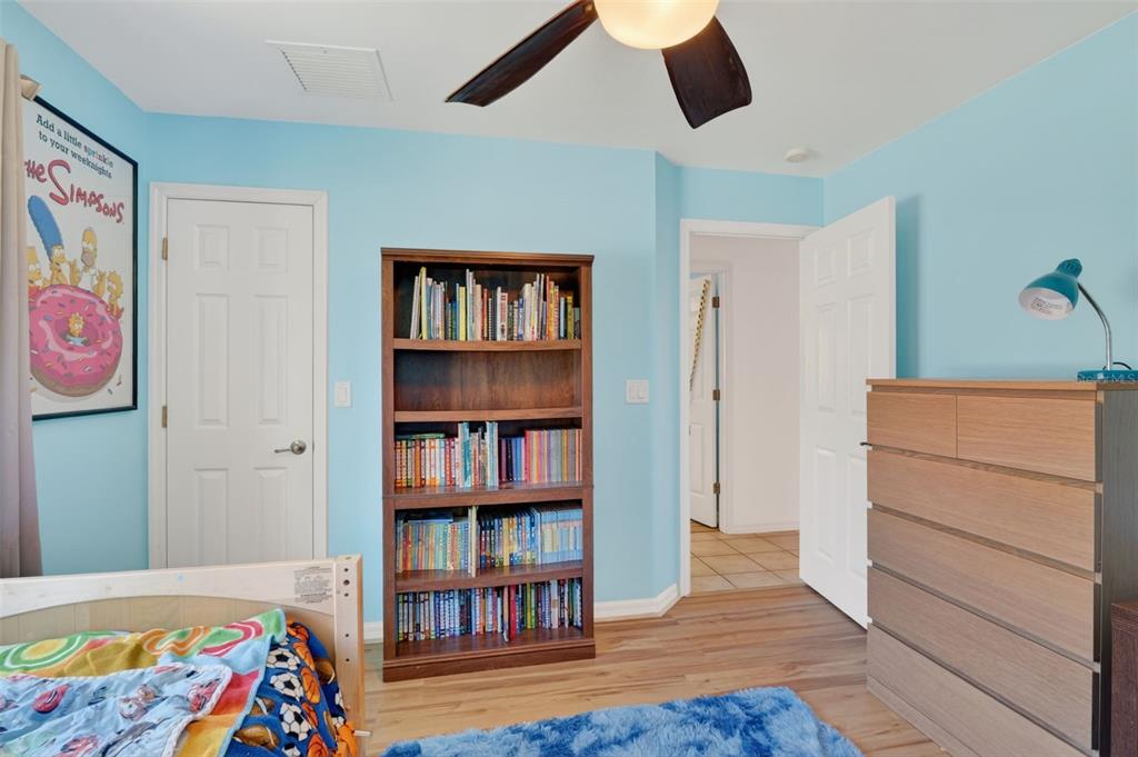 A bedroom with light blue walls, a wooden bookshelf, a dresser, and a ceiling fan — 3809 AGUALINDA BOULEVARD, CAPE CORAL, FL