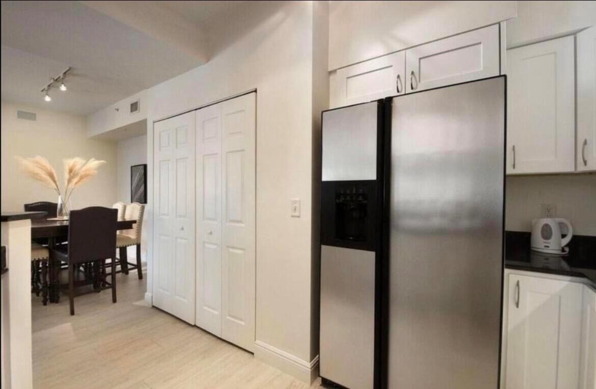 A kitchen with white cabinets and a stainless steel refrigerator next to a dining area — 802 W Windward Way # 216, Lantana FL 33462, LANTANA, FL