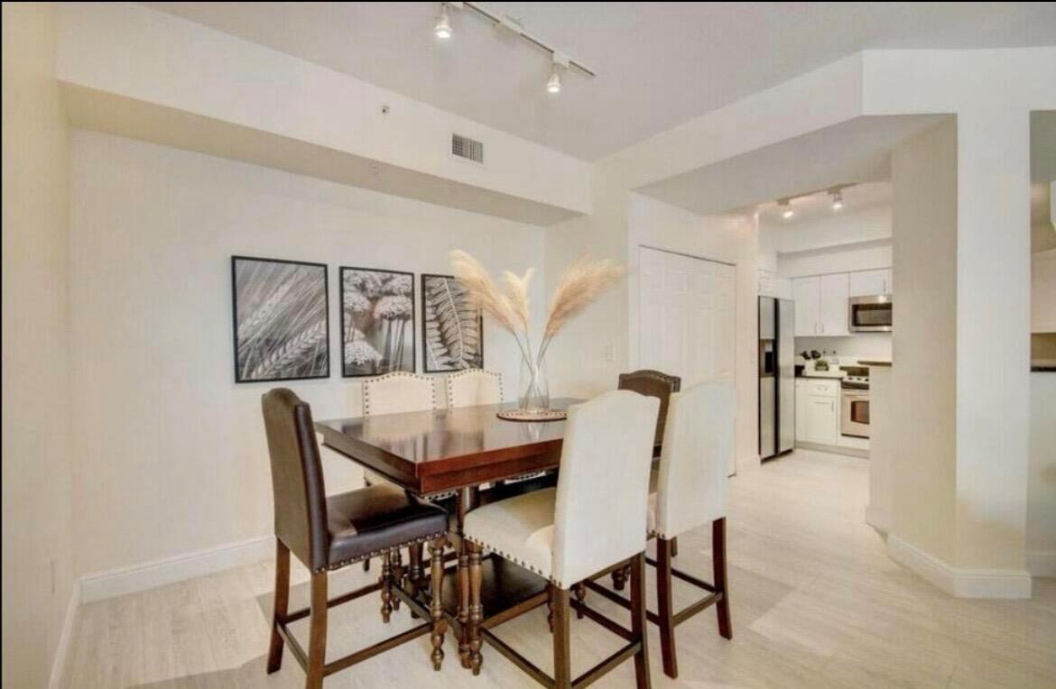 A dining area with a wooden table, upholstered chairs, and wall art near a kitchen — 802 W Windward Way # 216, Lantana FL 33462, LANTANA, FL