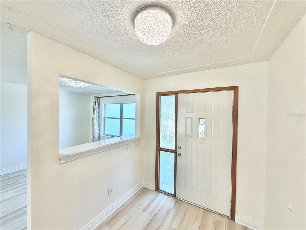 A bright entryway features light wood-look flooring, a white front door, and a wall cutout — 17469 SW 35TH AVENUE ROAD, OCALA, FL