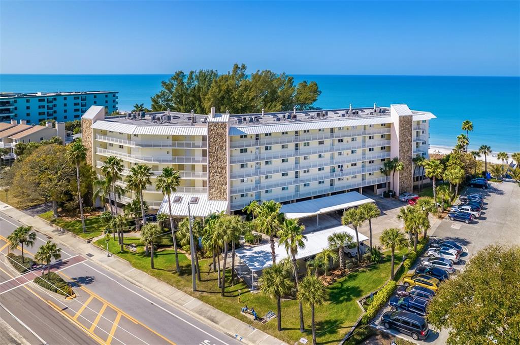 An aerial view of a multi-story apartment building with a parking lot near the ocean — 2504 GULF BOULEVARD UNIT 304, INDIAN ROCKS BEACH, FL
