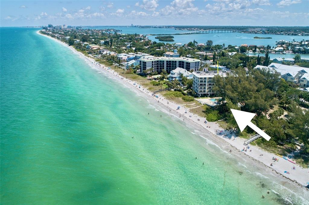 An aerial view shows a beachfront condominium complex surrounded by trees along the coast — 2504 GULF BOULEVARD UNIT 304, INDIAN ROCKS BEACH, FL