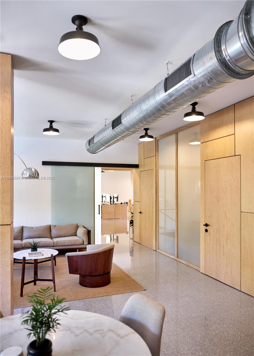 A modern office lounge features light wood paneling, a large metal air duct, and furniture — 1800 N Miami Ave, Miami FL 33136, MIAMI, FL