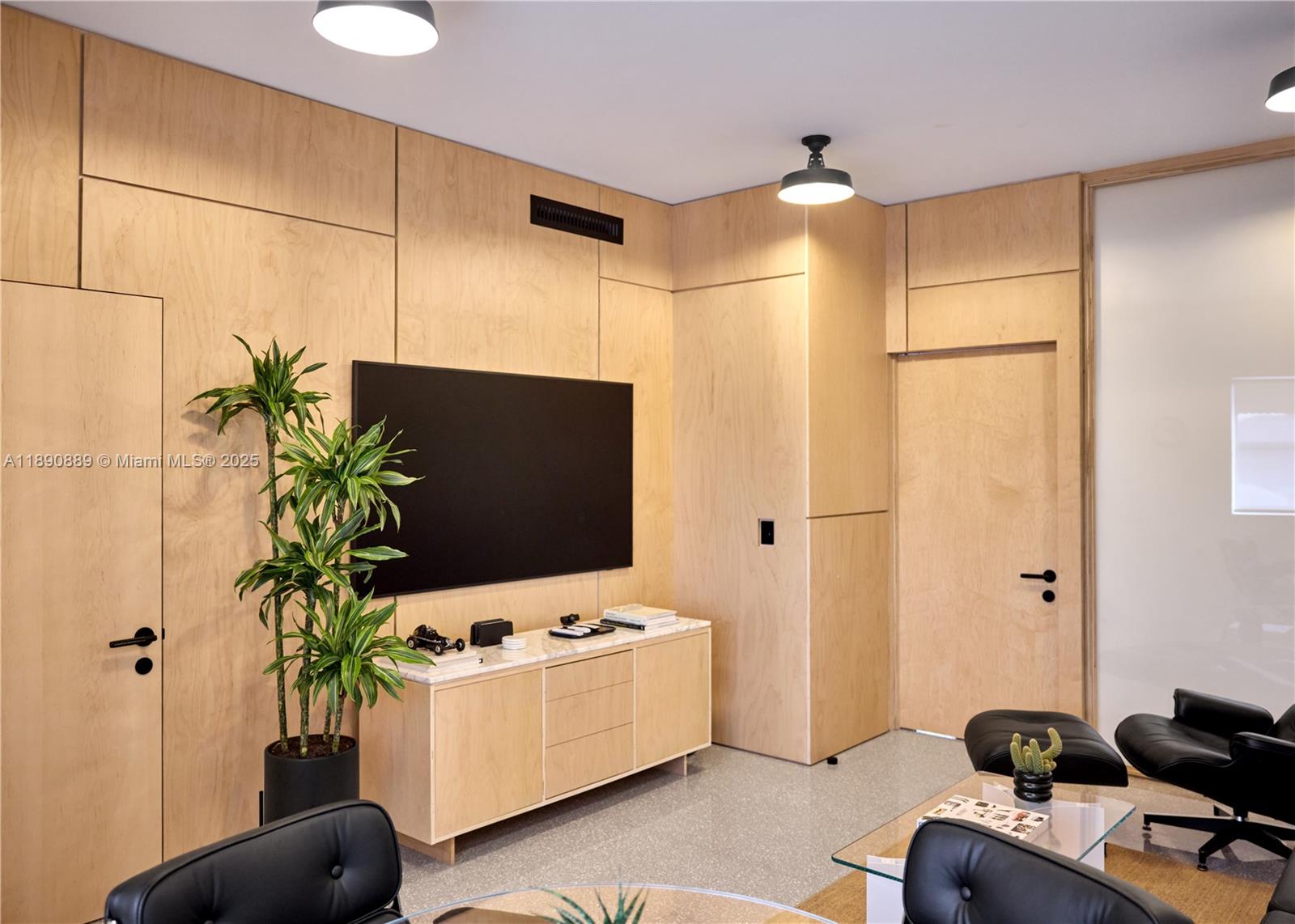 A modern office features light wood paneling, a wall-mounted television, and black leather chairs — 1800 N Miami Ave, Miami FL 33136, MIAMI, FL