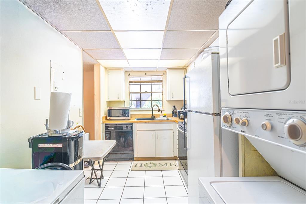 A kitchen features white cabinets, a stacked washer-dryer unit, and a drop ceiling — 709 RUSSELL LANE UNIT 222, BRANDON, FL