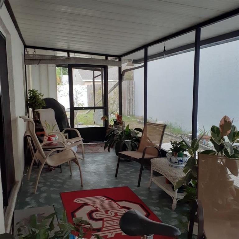 A screened-in porch with a concrete floor, patio furniture, and a red area rug — 13427 LARAWAY DRIVE, RIVERVIEW, FL