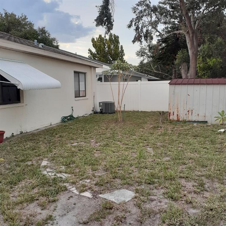 A backyard features a white house with an awning, a shed, and a vinyl fence — 13427 LARAWAY DRIVE, RIVERVIEW, FL