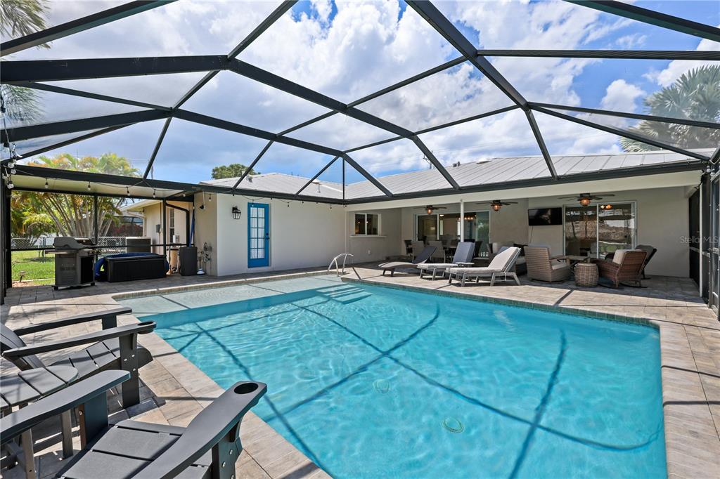 A screened-in patio features a swimming pool, lounge chairs, and a covered outdoor seating area — 5215 PELICAN BOULEVARD, CAPE CORAL, FL