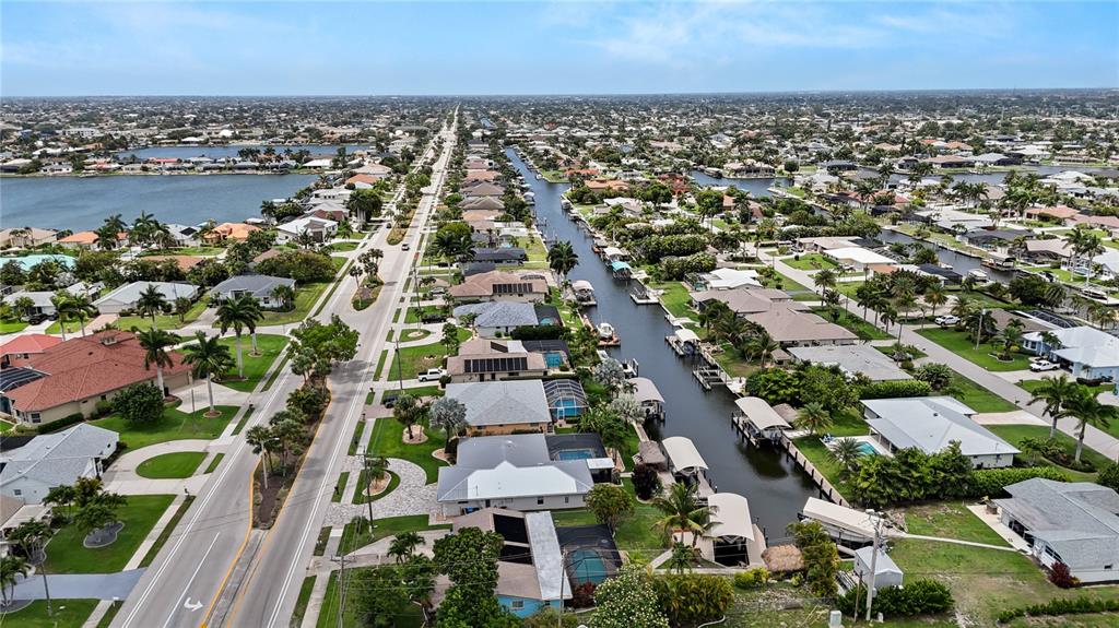 An aerial view shows a residential neighborhood with houses lining a canal and a road — 5215 PELICAN BOULEVARD, CAPE CORAL, FL
