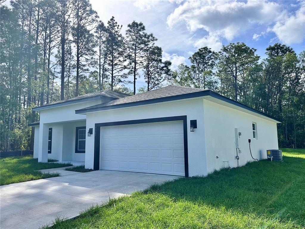 A white single-story house with a black-trimmed garage and a concrete driveway sits near trees — 7983 N POCONO DRIVE, CITRUS SPRINGS, FL