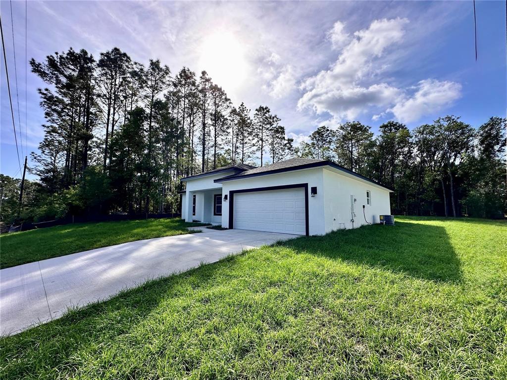 A white single-story house with a two-car garage and a concrete driveway — 7983 N POCONO DRIVE, CITRUS SPRINGS, FL