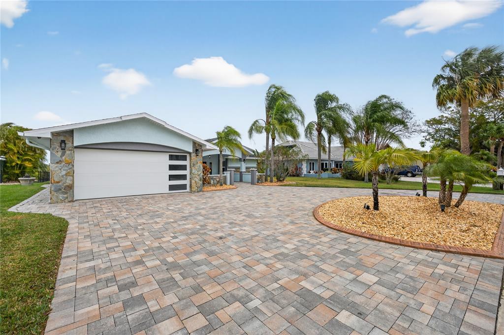 A paved driveway leads to a garage with stone accents and several palm trees — 4111 MARINE PARKWAY, NEW PORT RICHEY, FL