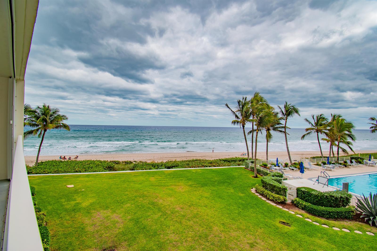 A view from a balcony overlooking a grassy lawn, swimming pool, beach, and ocean — 3101 S Ocean Boulevard # 322, Highland Beach FL 33487, HIGHLAND BEACH, FL