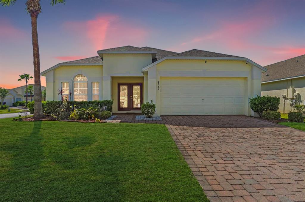 A single-story house with a yellow exterior, a paved driveway, and a front lawn — 4715 CUMBRIAN LAKES DRIVE, KISSIMMEE, FL