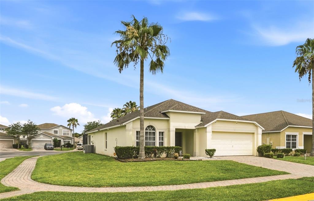 A single-story suburban house with a palm tree, a two-car garage, and a paved walkway — 4715 CUMBRIAN LAKES DRIVE, KISSIMMEE, FL