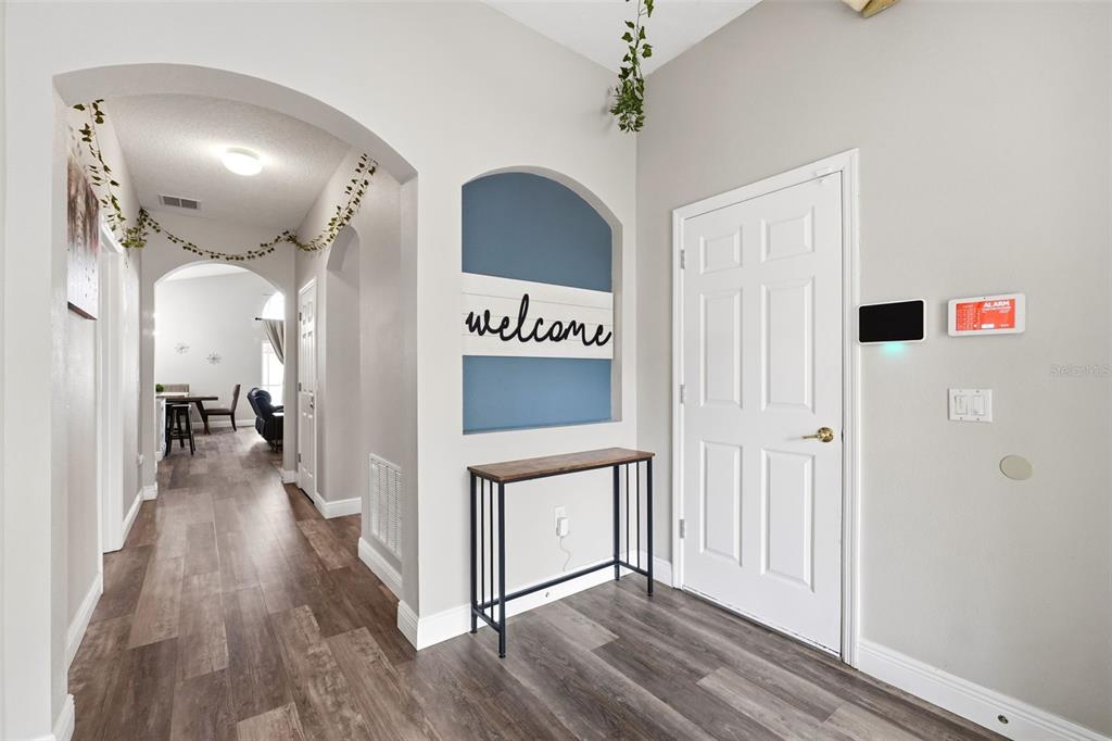 An entryway features wood-look flooring, a blue arched wall niche, and a console table — 4715 CUMBRIAN LAKES DRIVE, KISSIMMEE, FL