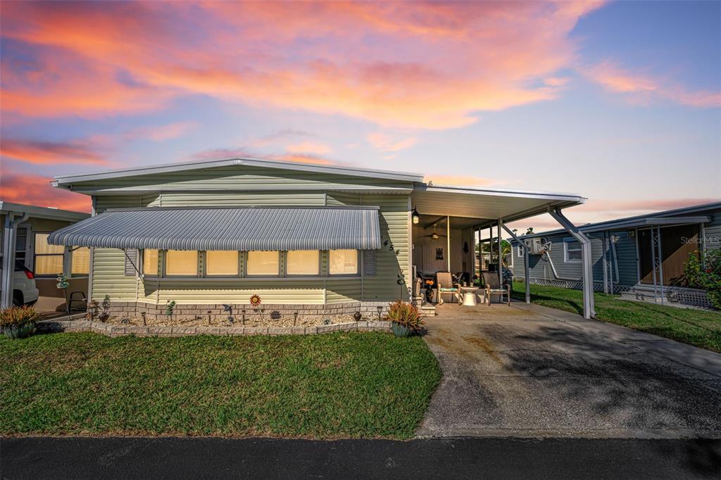 A light green manufactured home with an attached carport and a metal window awning — 4454 TUCKER SQUARE, NEW PORT RICHEY, FL