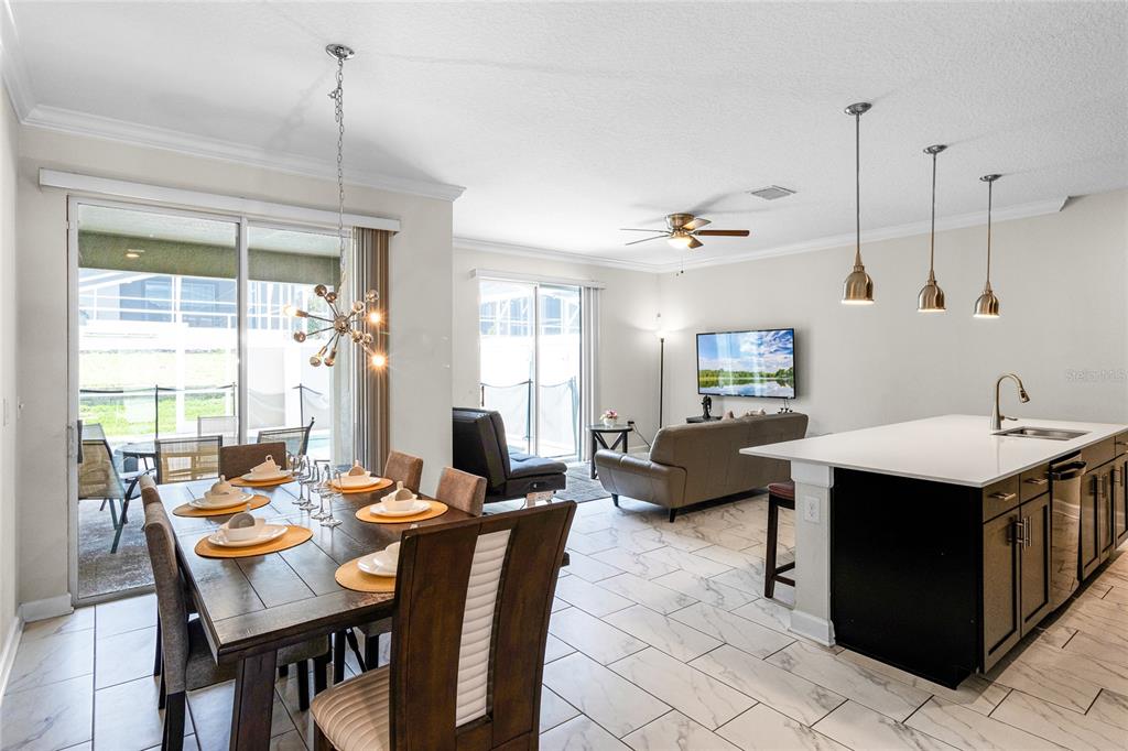 An open-concept kitchen, dining area, and living room featuring tile floors and sliding glass doors — 1224 CHALLENGE DRIVE, DAVENPORT, FL