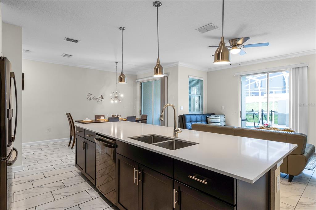 A kitchen island with a white countertop overlooks a dining area and living room — 1224 CHALLENGE DRIVE, DAVENPORT, FL