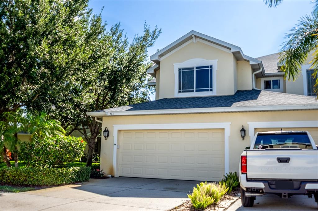 A beige two-story house features a two-car garage and a white pickup truck parked outside — 403 HARBOR RIDGE DRIVE, PALM HARBOR, FL