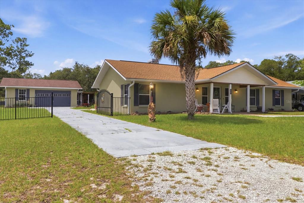 A single-story house with a detached garage, a gravel driveway, and a prominent palm tree — 6928 W HAMILL COURT, HOMOSASSA, FL