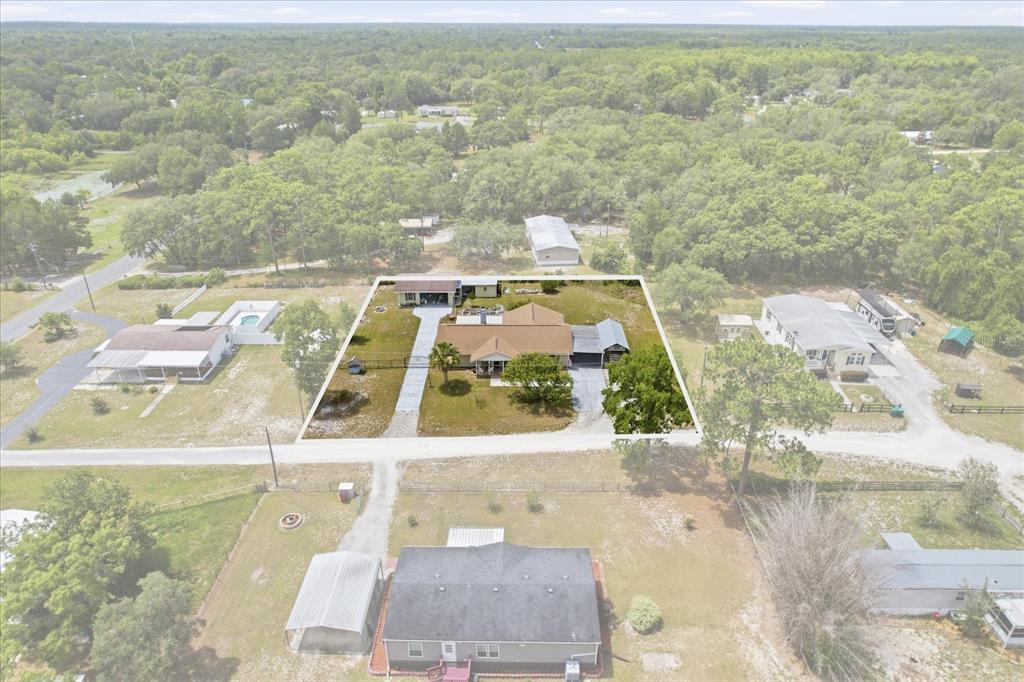 An aerial view shows a single-story house with a brown roof and attached carport — 6928 W HAMILL COURT, HOMOSASSA, FL