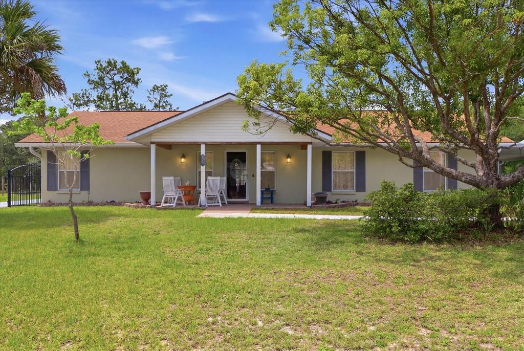 A single-story house with a covered front porch, light-colored siding, and a grassy yard — 6928 W HAMILL COURT, HOMOSASSA, FL