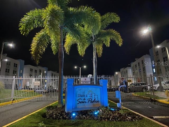 An illuminated sign for Chales de San Pedro stands before palm trees at night — CHALETS DE SAN PEDRO SAN GABRIEL UNIT 402, FAJARDO, PR
