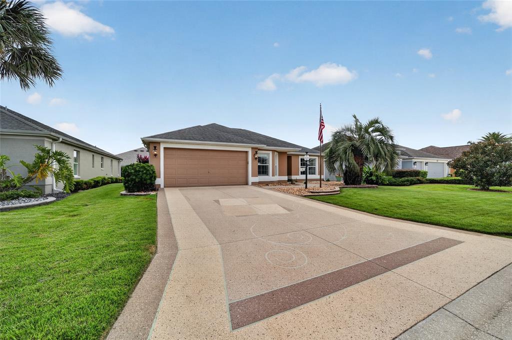 A single-story house with a tan garage, a decorative concrete driveway, and a manicured lawn — 726 BRADFORD LOOP, THE VILLAGES, FL