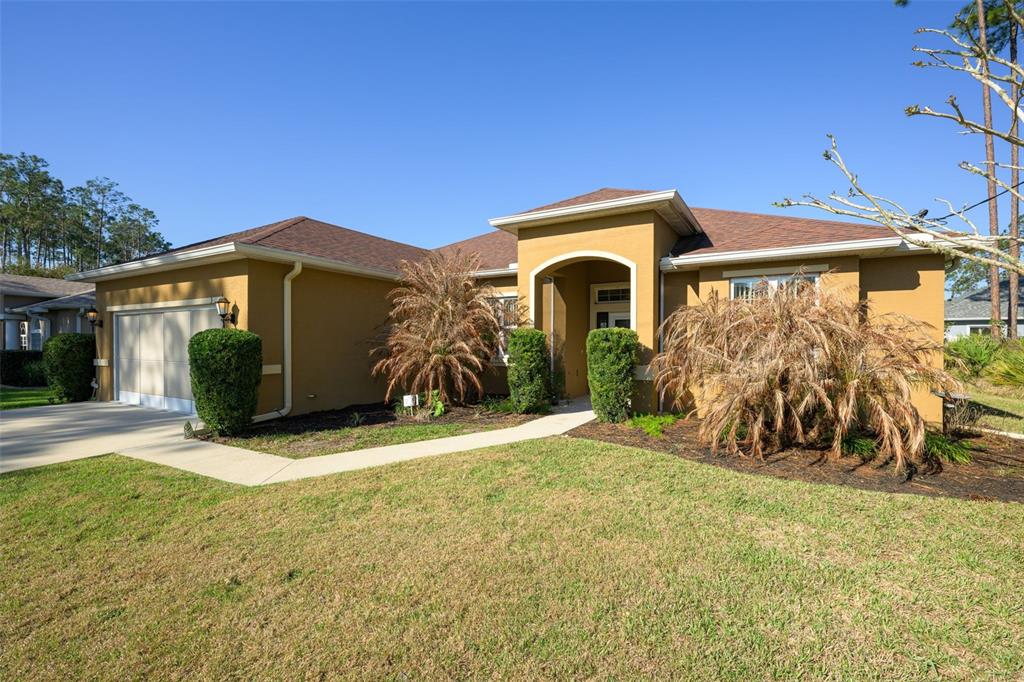 A single-story house with a tan stucco exterior, a two-car garage, and a front walkway — 3 LAKE CHARLES PLACE, PALM COAST, FL