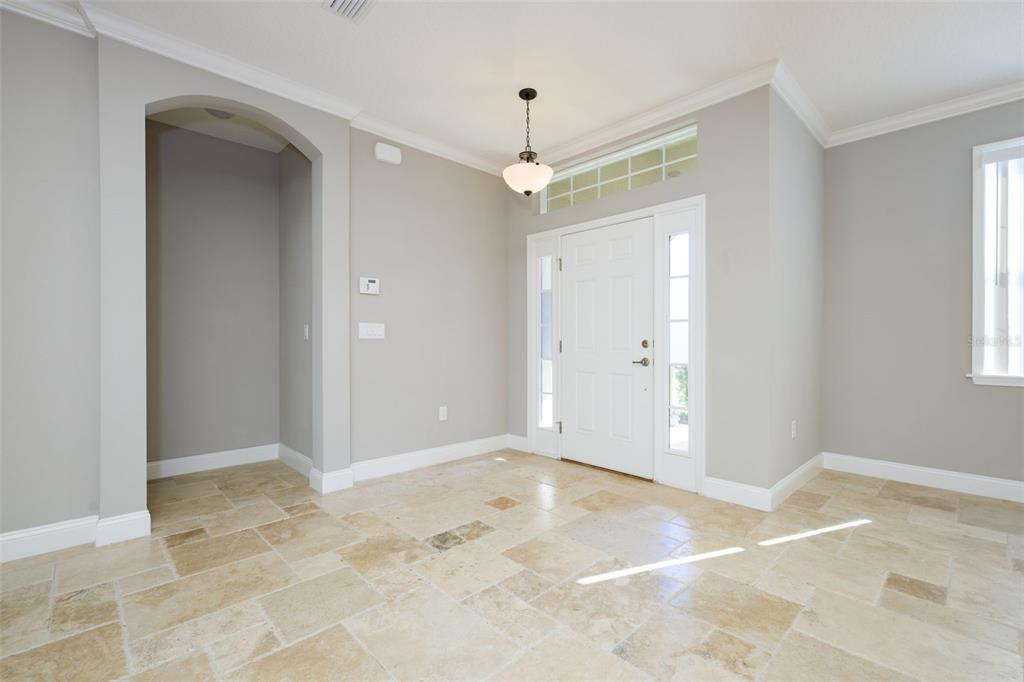 An entryway features light-colored tile flooring, a white front door with sidelights, and gray walls — 3 LAKE CHARLES PLACE, PALM COAST, FL