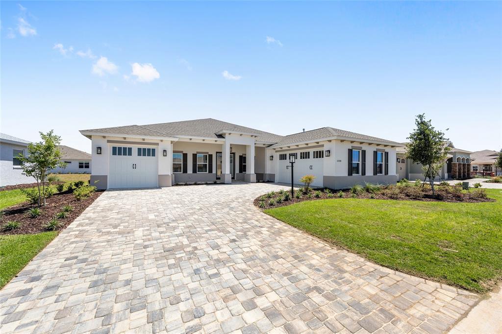 A single-story house with a paved driveway, two garages, and light-colored stucco exterior walls — 10288 SW 85TH PLACE ROAD, OCALA, FL