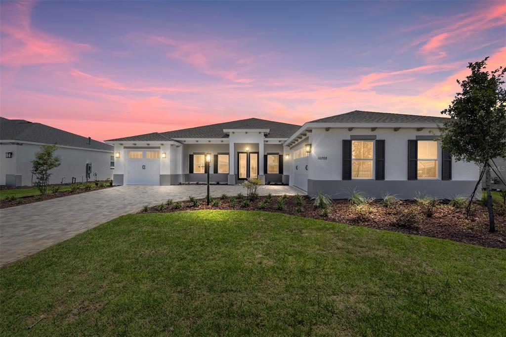 A single-story house with a paved driveway, white stucco exterior, and a three-car garage — 10288 SW 85TH PLACE ROAD, OCALA, FL