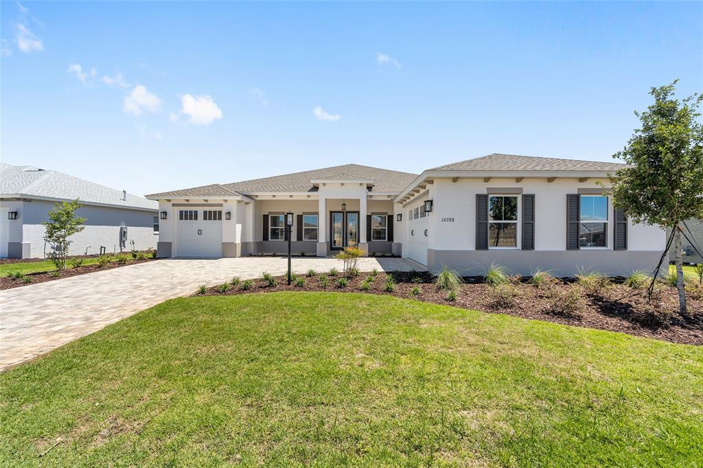A single-story house with a paved driveway, two-car garage, and a light-colored stucco exterior — 10288 SW 85TH PLACE ROAD, OCALA, FL