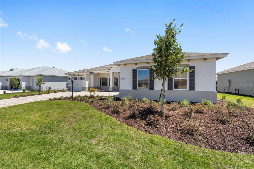 A single-story house with a light-colored exterior, dark shutters, and a landscaped front yard — 10288 SW 85TH PLACE ROAD, OCALA, FL