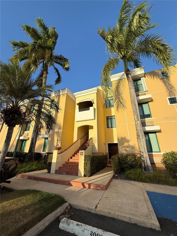 A three-story yellow apartment building features a central staircase and tall palm trees — Edificio 8 EL DORADO CLUB UNIT 30-03, VEGA ALTA, PR