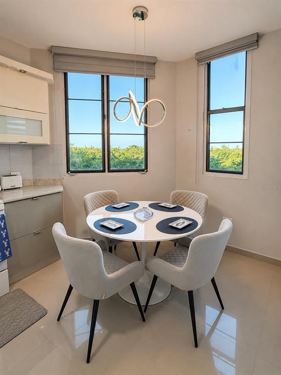 A dining area features a round white table, four upholstered chairs, and a modern pendant light — Edificio 8 EL DORADO CLUB UNIT 30-03, VEGA ALTA, PR