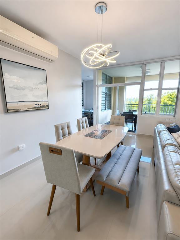 A dining area features a modern light fixture, a rectangular table, chairs, and a bench — Edificio 8 EL DORADO CLUB UNIT 30-03, VEGA ALTA, PR