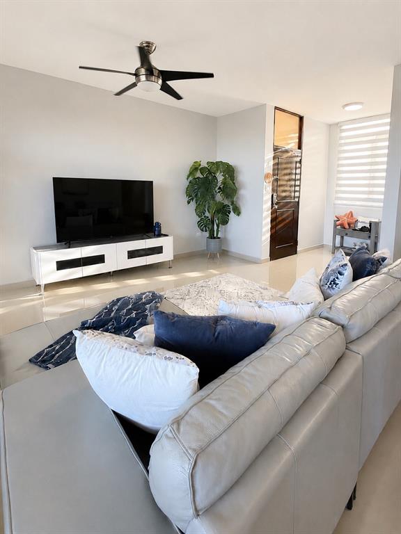 A living room features a large gray sectional sofa, a television on a white console, and a plant — Edificio 8 EL DORADO CLUB UNIT 30-03, VEGA ALTA, PR