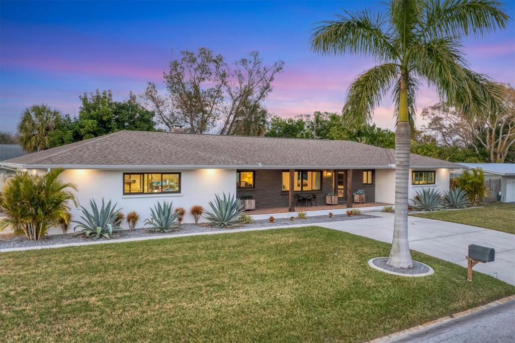 A single-story house with a white exterior, dark stone facade, and a covered front porch — 2411 VALENCIA DRIVE, SARASOTA, FL