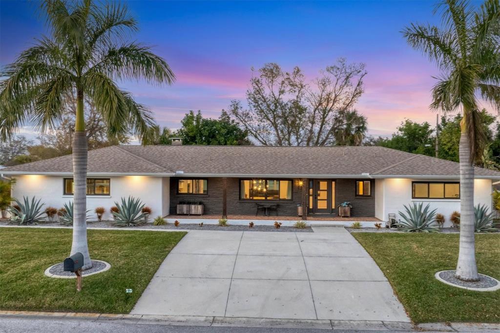 A single-story house with a white and dark stone facade, palm tree, and manicured lawn — 2411 VALENCIA DRIVE, SARASOTA, FL