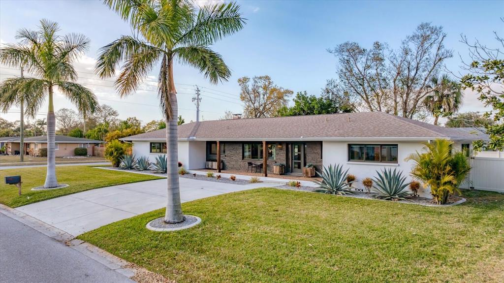 A single-story house with a white and dark brick exterior, palm trees, and a driveway — 2411 VALENCIA DRIVE, SARASOTA, FL