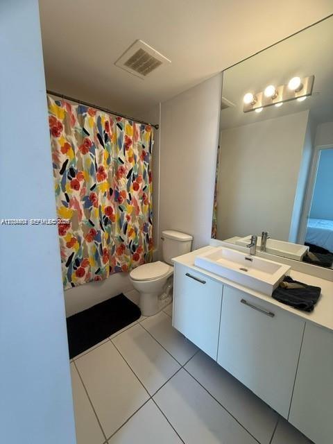 A bathroom features a white vanity, a toilet, and a colorful floral shower curtain — 151 SE 1st St # 2906, Miami FL 33131, MIAMI, FL