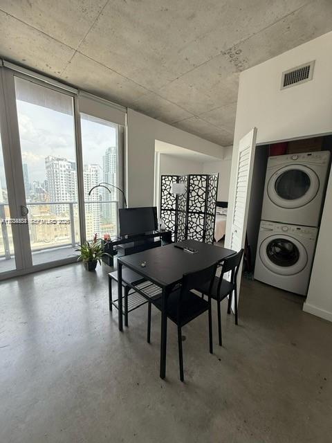 A modern apartment living area features a dining table, a room divider, and stacked laundry appliances — 151 SE 1st St # 2906, Miami FL 33131, MIAMI, FL