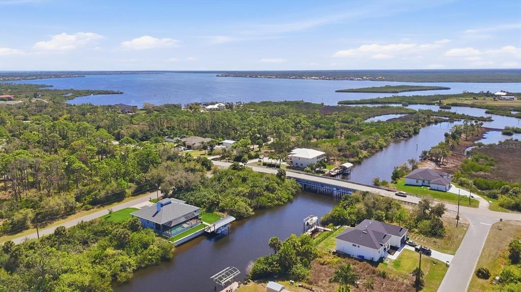 A screened-in pool patio overlooks a canal with a boat lift and nearby houses — 1022 BEEKMAN CIRCLE, PORT CHARLOTTE, FL