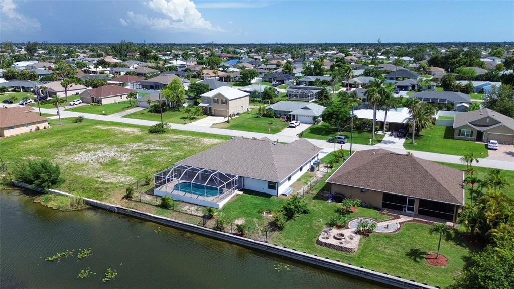 An aerial view shows two waterfront houses with pools and backyards in a suburban neighborhood — 619 SW 26TH TERRACE, CAPE CORAL, FL