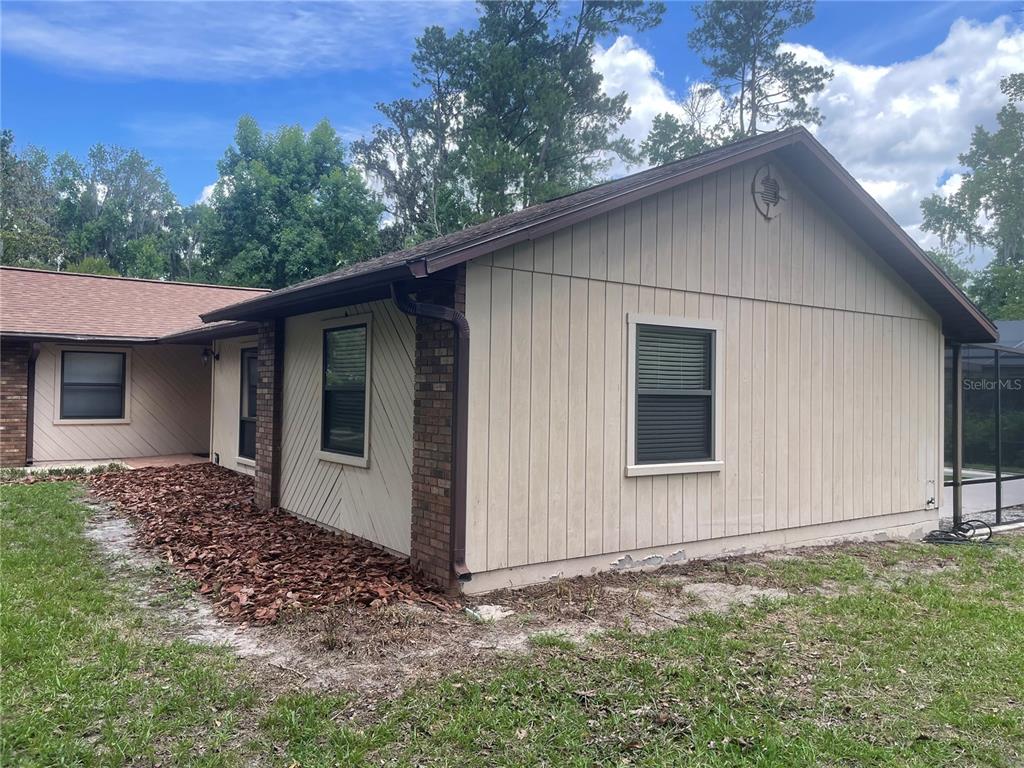 A red front door with glass panels sits next to a sidelight on a tiled porch — 2421 NW 106TH DRIVE, GAINESVILLE, FL