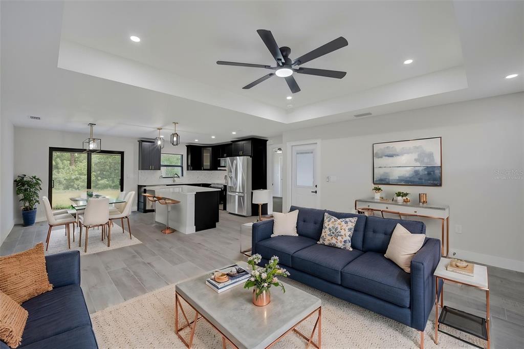 An open-concept living room and kitchen featuring dark cabinetry, a central island, and blue sofas — 19226 BRANDON AVENUE, PORT CHARLOTTE, FL
