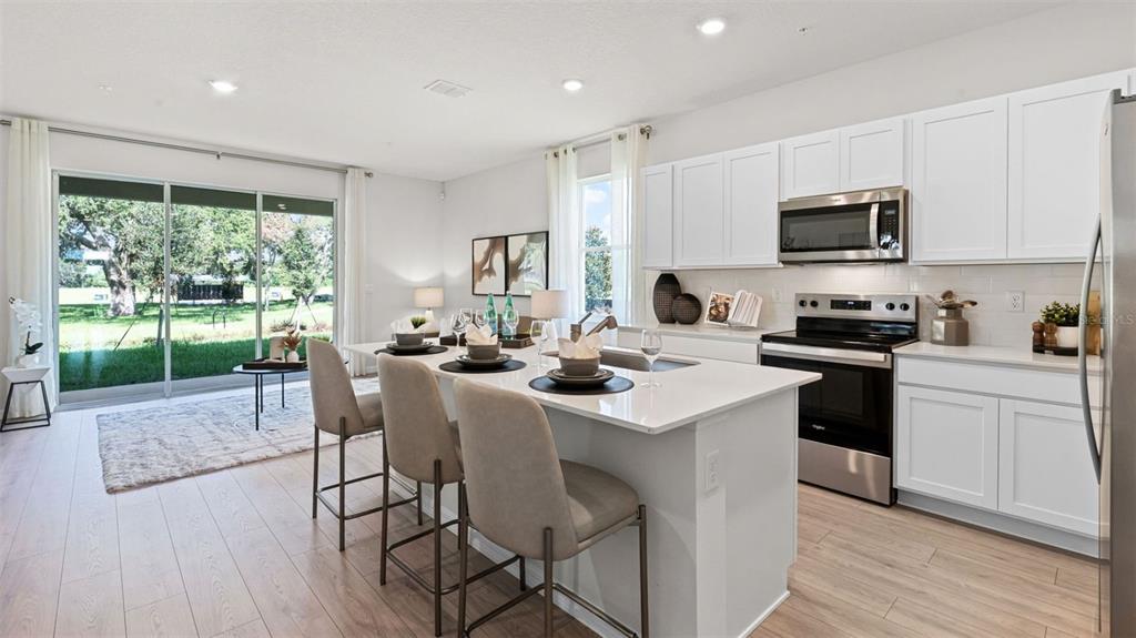 A modern kitchen features white cabinets, a central island with bar seating, and sliding doors — 3498 CHROMA STREET, ORLANDO, FL