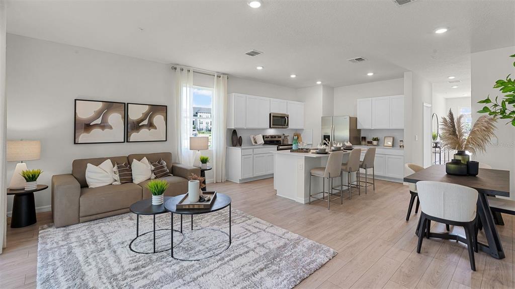 An open-concept living room and kitchen featuring white cabinetry, a kitchen island, and wood flooring — 3498 CHROMA STREET, ORLANDO, FL